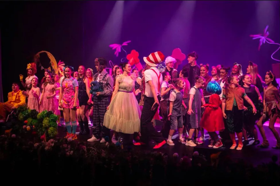 a large group of young people perform on a theatre stage