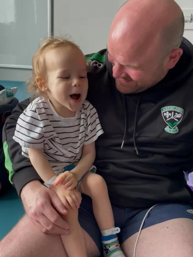 a dad holds his son on his knee