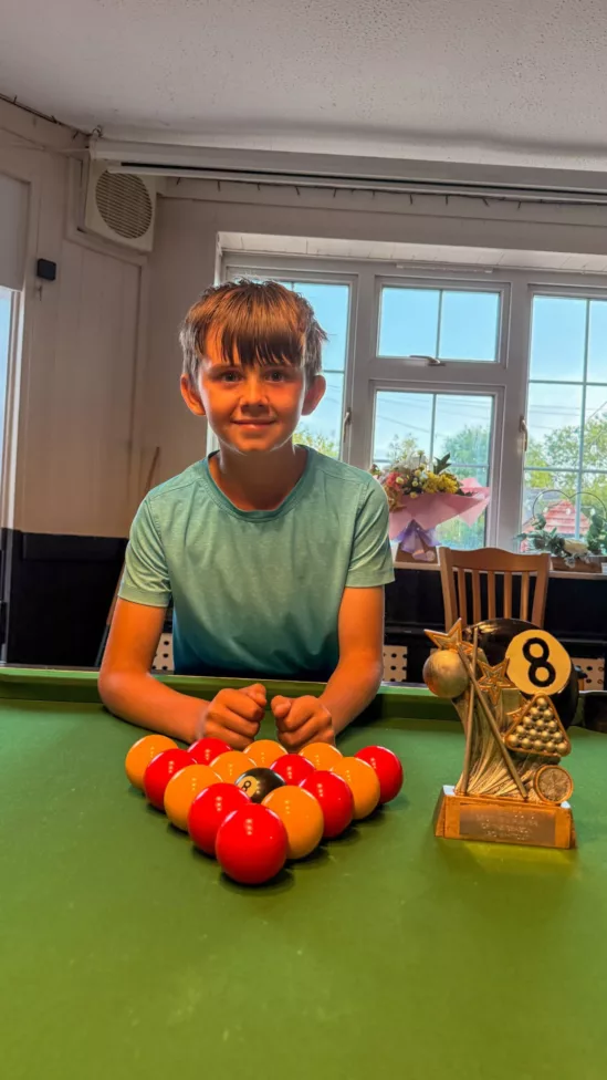 a young boy stood at a pool table