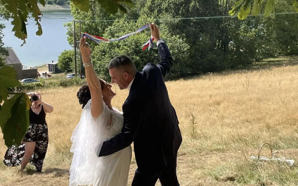 a man and woman hug during their wedding outside in field