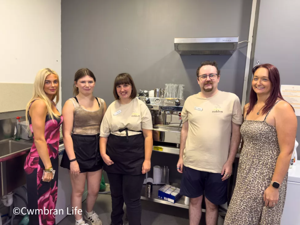 four woman and a man stood by a coffee machine