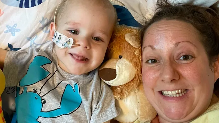a little boy and his mum smile up at the camera