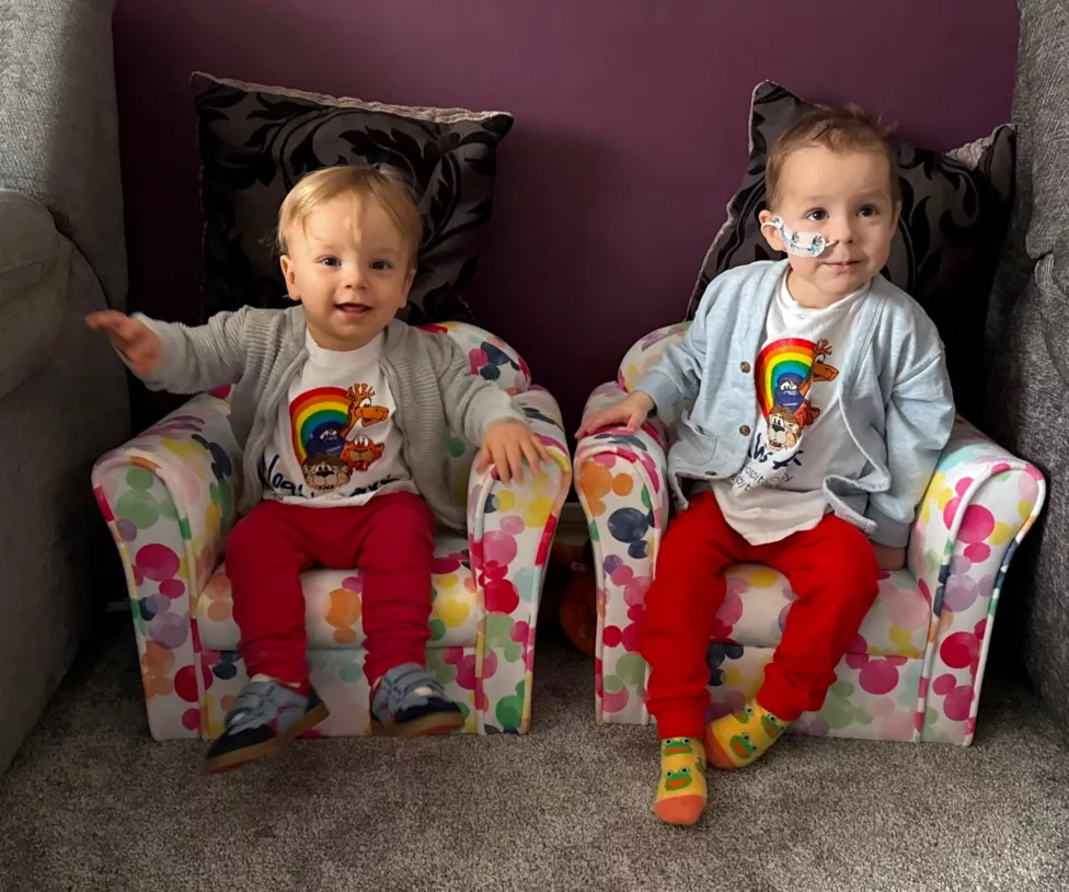 two young boys sit on small chairs and smile at the camera