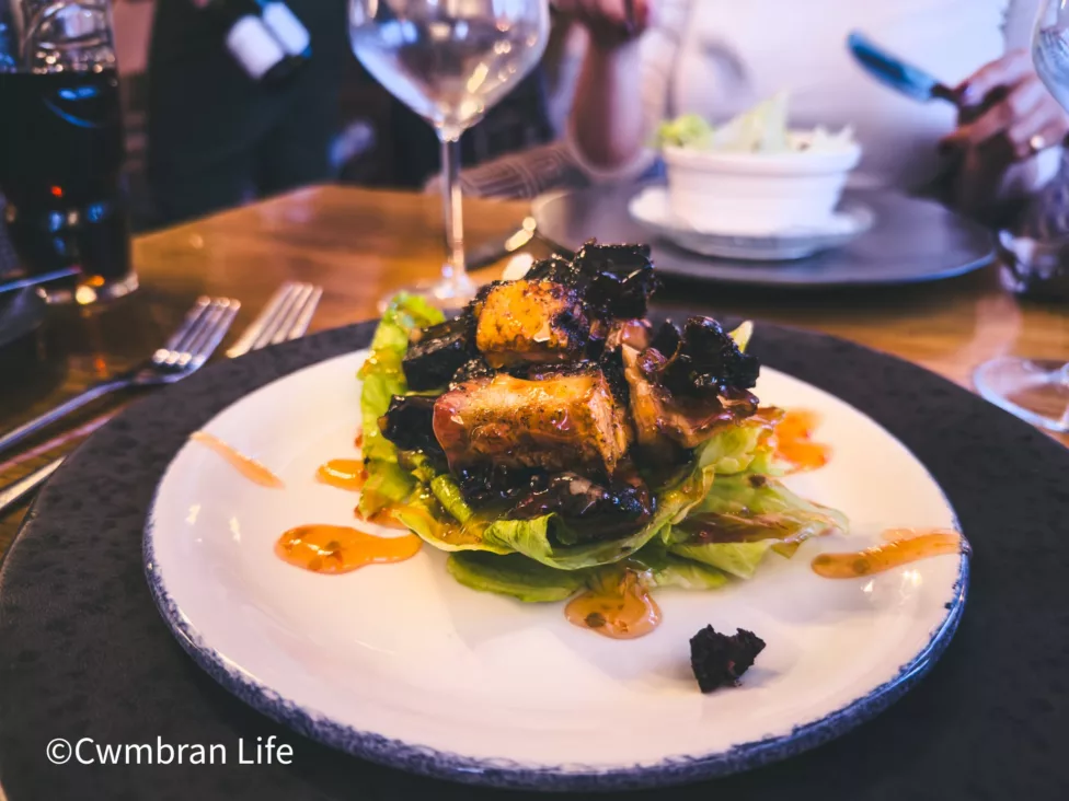 a photo of a plate of pork bites on lettuce