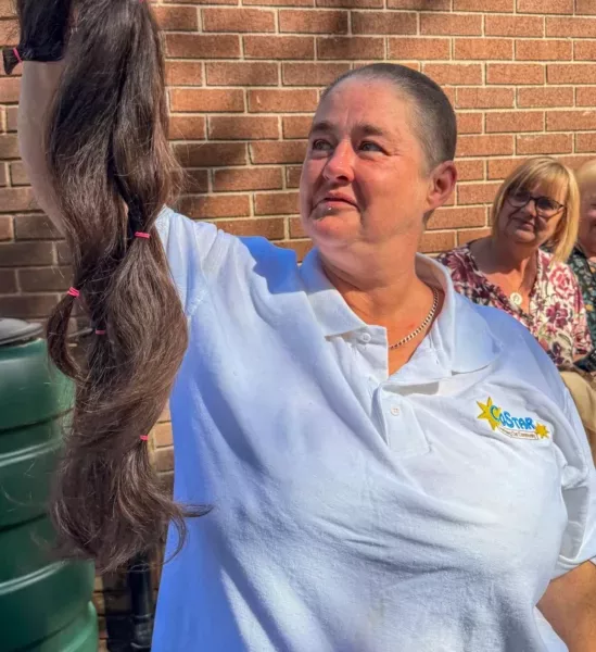 a woman holds up a bunch of hair she's had cut off her head