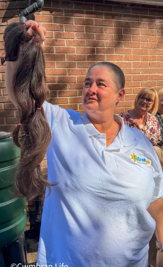 a woman holds up a bunch of hair she's had cut off her head