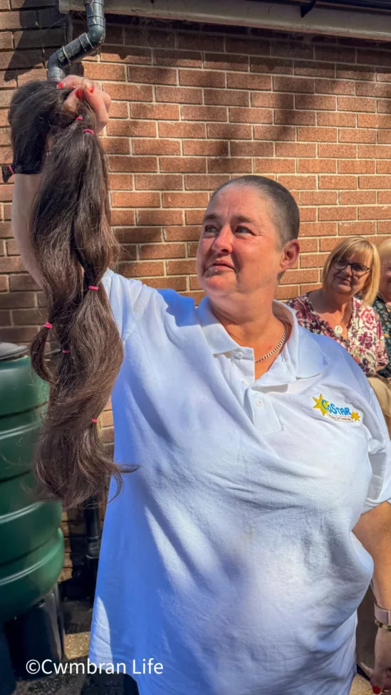 a woman holds up a bunch of hair she's had cut off her head