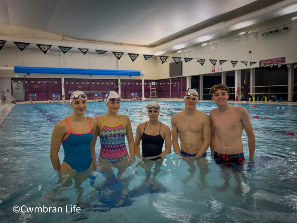 six swimmers stand in a pool